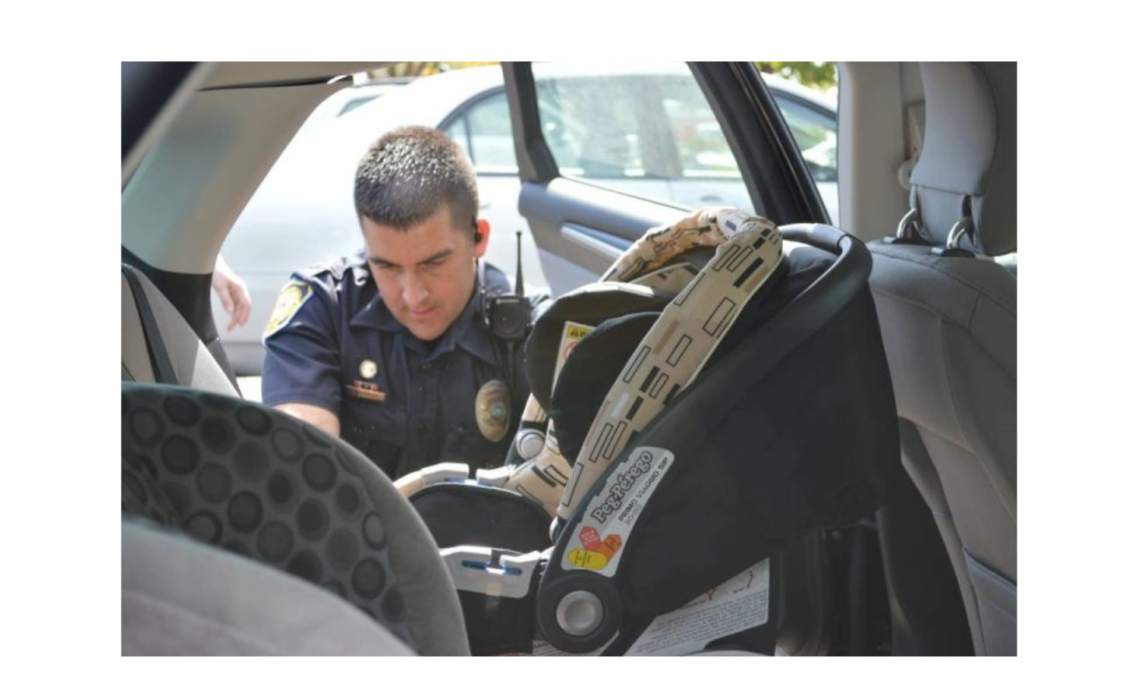 A police officer installs a car seat in a vehicle.